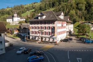 ein großes weißes Gebäude mit Autos auf einem Parkplatz in der Unterkunft Hotel Alpina in Unterschächen