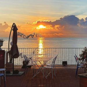 einen Tisch und Stühle auf einem Balkon mit Blick auf den Sonnenuntergang in der Unterkunft Made in Sicily Santa Tecla in Acireale