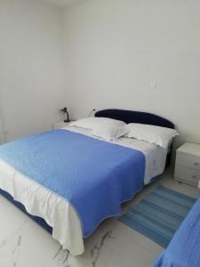 a bedroom with a large bed with a blue blanket at Apartment Villa Bajna in Živogošće