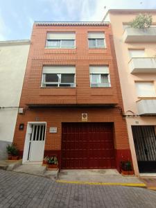 un edificio de ladrillo rojo con dos puertas de garaje en Casa Rural Eric, en Les Coves de Vinroma