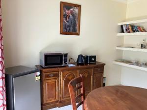 cocina con armario de madera, microondas y mesa en James Court Suite, en Rutherglen