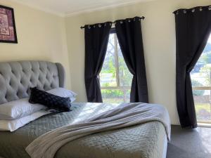 a bedroom with a bed with black curtains and a window at James Court Suite in Rutherglen