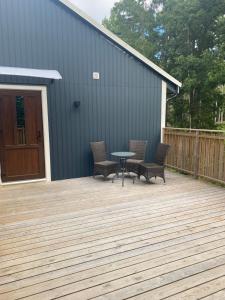 a patio with three chairs and a table on a deck at Sjölanda in Sjuntorp