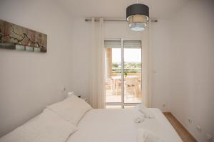 Habitación blanca con cama y balcón. en Cristina IV, en Campoamor