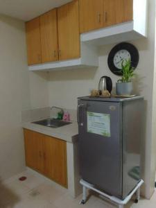 a kitchen with a refrigerator and a sink and a clock at Studio for Rent near Ortigas Extension in Cainta