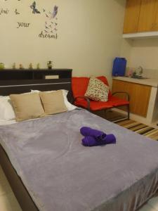 a bed with purple gloves sitting on top of it at Studio for Rent near Ortigas Extension in Cainta
