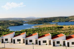 a row of white buildings with a lake in the background at Monte Bela Vista in Macedo de Cavaleiros