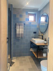 La salle de bains est pourvue de carrelage bleu, d'un lavabo et d'un miroir. dans l'établissement Ancient & Modern, à Šibenik