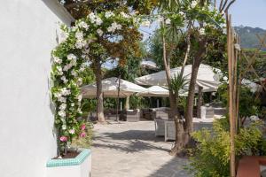 伊斯基亞的住宿－聖弗朗西斯科酒店，拱门,上面有白色的花朵,桌子和雨伞