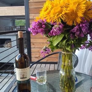 a bottle of wine sitting on a table with a vase of flowers at Roshka Apartment 307 in Gudauri