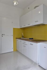 a kitchen with white cabinets and a yellow wall at 4-teen in Jagodina