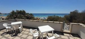 un patio con due tavoli e sedie e la spiaggia di Enjoy Beach Porto Cesareo a Porto Cesareo