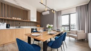 kuchnia i jadalnia z drewnianym stołem i niebieskimi krzesłami w obiekcie Flatbook - Yacht Harbor Apartments Sol Marina w mieście Wiślinka +8 zdjęć