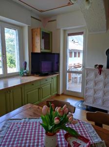 une cuisine avec une table et un vase de fleurs dans l'établissement Appartamento Vanoi nel cuore verde del Trentino, à Canal San Bovo