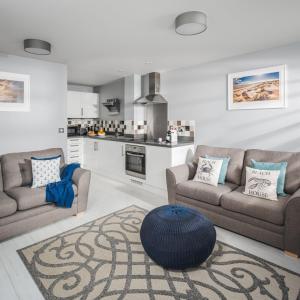 a living room with two couches and a kitchen at Salt Bay in Camber