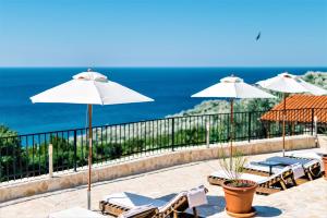 a patio with umbrellas and chairs and the ocean at Holiday Park Olive Tree in Ulcinj