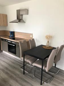 cocina con mesa negra, sillas y encimera en Ferienwohnung Marli en Marburg an der Lahn