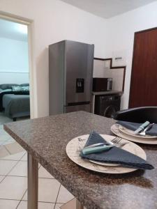 a kitchen with a table with plates and a refrigerator at The cozy 1 bedroom apartment in Midrand