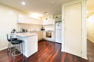 una cucina con armadietti bianchi e pavimenti in legno di Halls Gap Townhouse Escape a Halls Gap