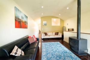 a living room with a black leather couch and a fireplace at Halls Gap Townhouse Escape in Halls Gap