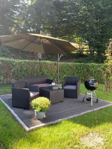 a patio with two chairs and an umbrella and a grill at Ferienwohnung Familie Heite in Olpe