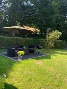 una sombrilla, sillas y una parrilla en un patio en Ferienwohnung Familie Heite, en Olpe