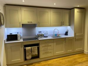 a kitchen with green cabinets and a sink and a microwave at Roundhill New Forest in Fordingbridge