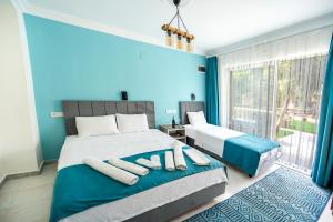 a blue bedroom with two beds and a window at Flower Hotel Patara in Patara