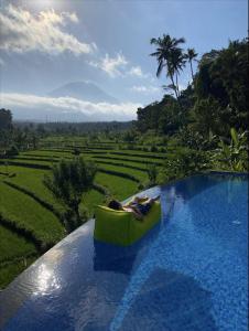 a pool with two people in a boat on the water at Villa di Bias in Tirtagangga
