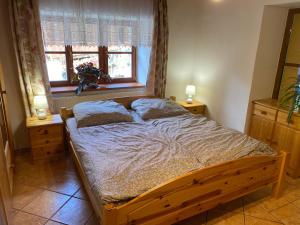 1 dormitorio con cama de madera, 2 lámparas y ventana en Apartmán u potoka, en Bujanov