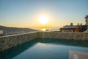 a swimming pool with the sunset in the background at Nova Butik Hotel Çeşme in Cesme