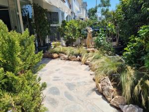 a garden with plants and a statue in front of a building at Parthenis Riviera Hotel in Athens