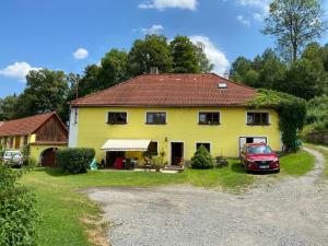 Bujanov的住宿－Apartmán u potoka，一座黄色的房子,前面有一辆汽车