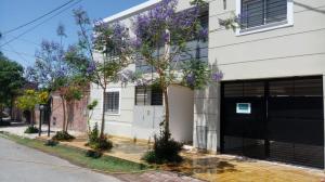 Una casa blanca con un árbol delante. en Abril Dptos Temporarios en San Juan