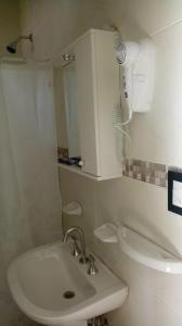 a white bathroom with a sink and a cabinet at Abril Dptos Temporarios in San Juan