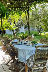 a table with a white table cloth and chairs and trees at la maison des Olivettes in Uzès