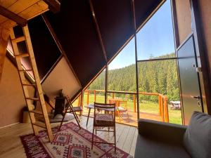 a room with a large window with a table and chairs at Casa din "Curtea cu cai" in Borsec
