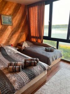 a bedroom with two beds and a large window at Къща за гости Ненийски in Lom