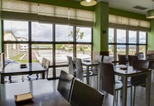 un restaurante con mesas, sillas y ventanas grandes en Hotel Playa de Laxe, en Laxe