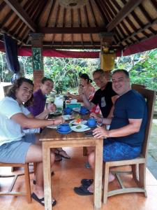 a group of people sitting around a wooden table at Nami House in Ubud