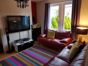 sala de estar con sofá de cuero y TV en Spacious 2 double bedrooms house for a relaxing stay. en South Kessock