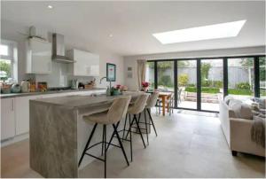 a kitchen and living room with a large island with bar stools at Beautiful 4 Double Bedroom House in Poole with Hot tub, near Sandbanks in Poole