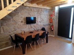 une table à manger avec des chaises et une télévision sur un mur en pierre dans l'établissement Casa da Florbela, à Fafe