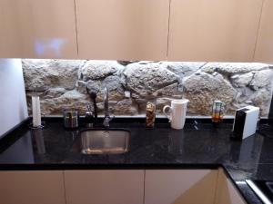 - un comptoir de cuisine avec un évier et un mur en pierre dans l'établissement Casa da Florbela, à Fafe