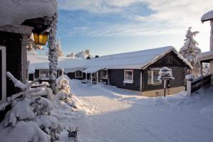 ein schneebedecktes Haus neben einem Gebäude in der Unterkunft Gammelgården in  Högfjället