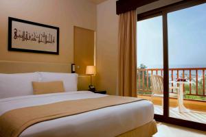 a bedroom with a large bed and a balcony at The Cove Rotana Resort - Ras Al Khaimah in Ras al Khaimah