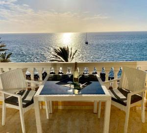 een tafel met een fles wijn en stoelen op de oceaan bij Sunset Ocean in Arguineguín