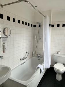 a bathroom with a tub and a toilet and a sink at Manor Hotel by Greene King Inns in Yeovil