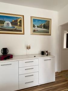 a white dresser in a room with paintings on the wall at Studio apartman BF in Slavonski Brod +4 photos