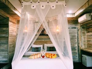 1 dormitorio con cama con dosel y cortinas blancas en Nanuk's Bungalows, en Nusa Lembongan